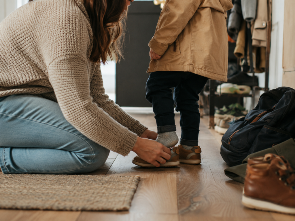 Parent helping a child put on shoes during a calm morning routine.