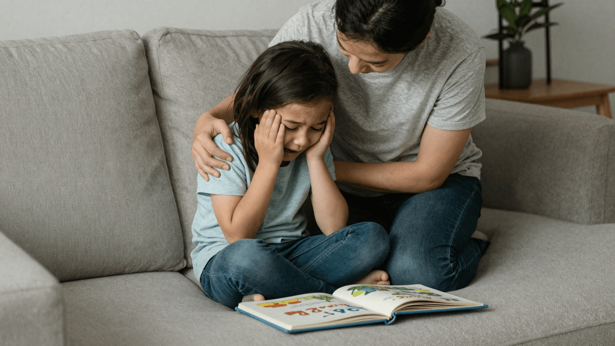 A parent kneeling to gently comfort a crying preschooler in a sunlit living room