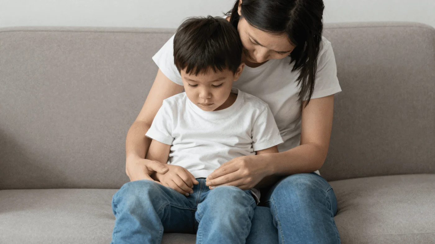 A parent and child sitting close together on a sofa in a calmer moment