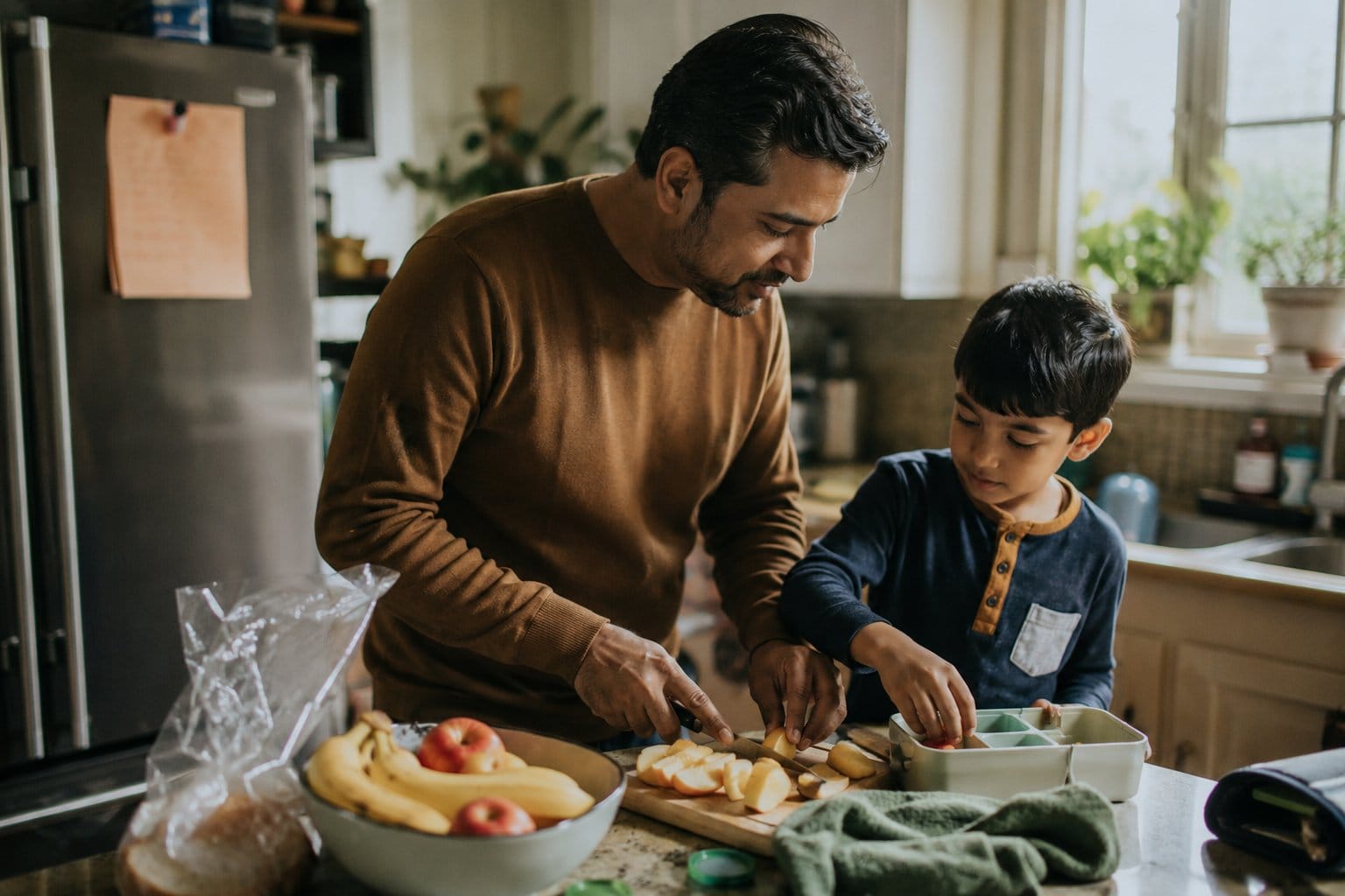 Father and son preparing fruit for a school lunchbox