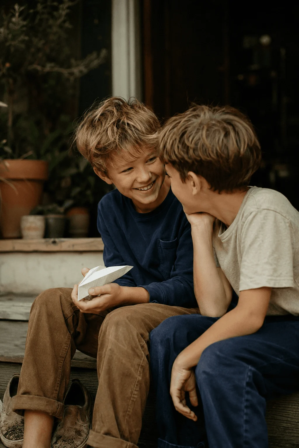 Two boys talking and laughing together on porch steps