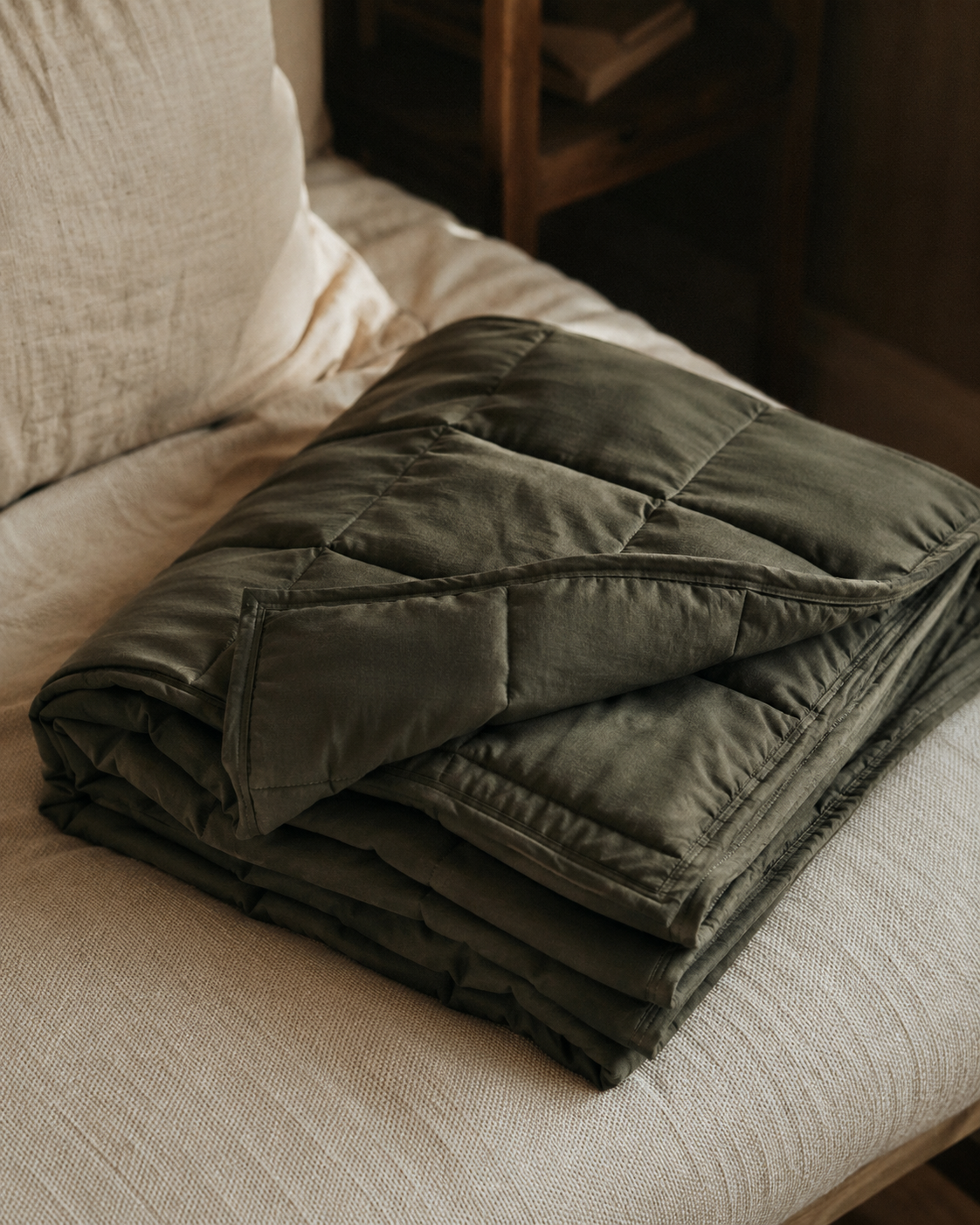 A weighted blanket folded on a bed, close-up on the stitching and fabric texture