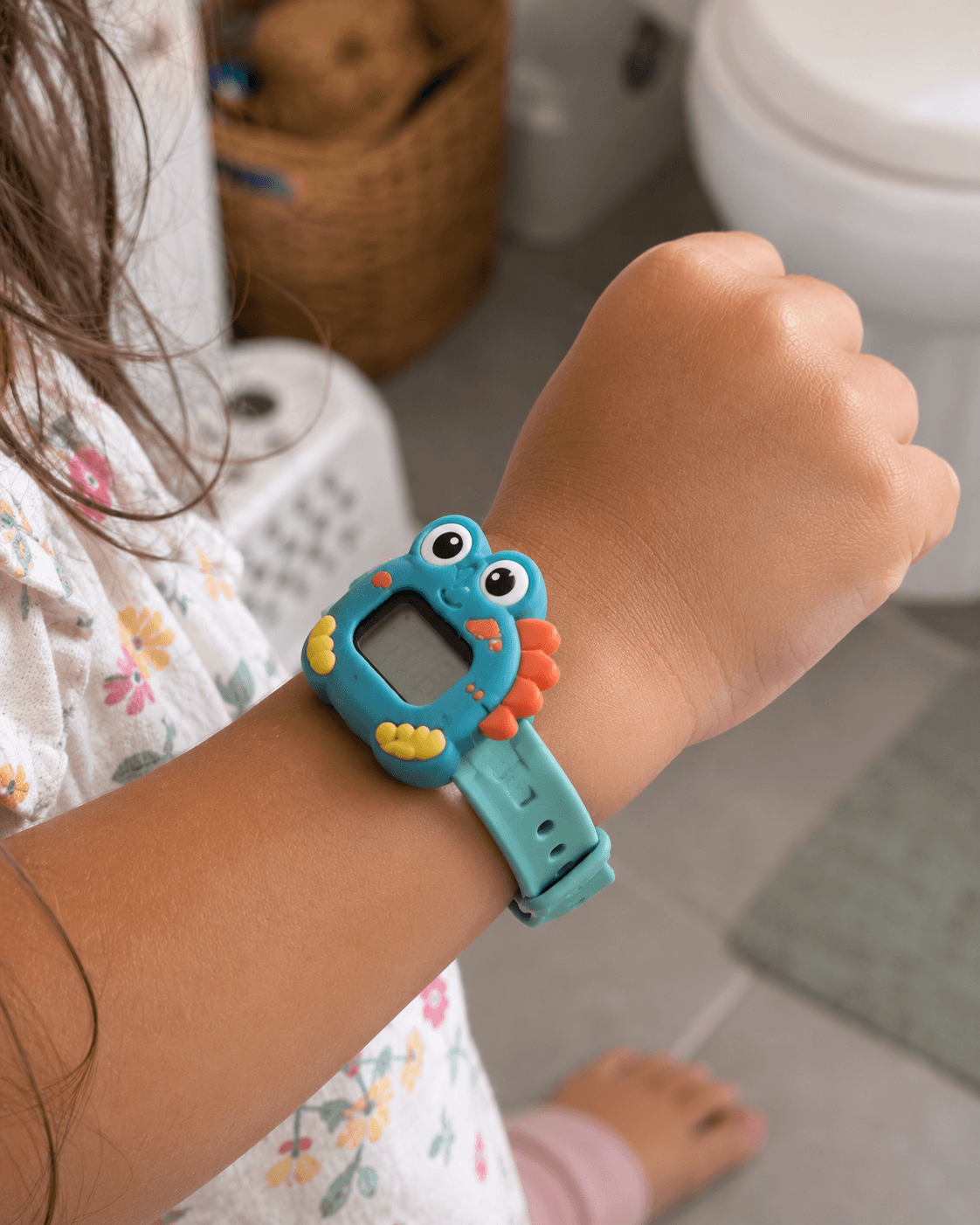 Close-up of a colourful digital potty training watch on a small toddler wrist