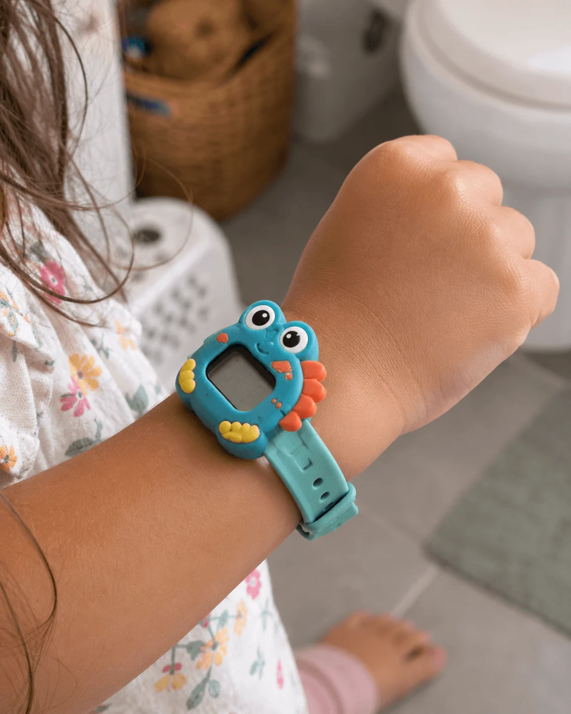 Close-up of a colourful digital potty training watch on a small toddler wrist