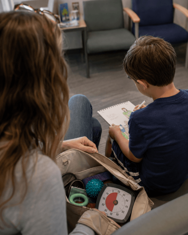 Parent opening a small sensory activity bag while a child draws