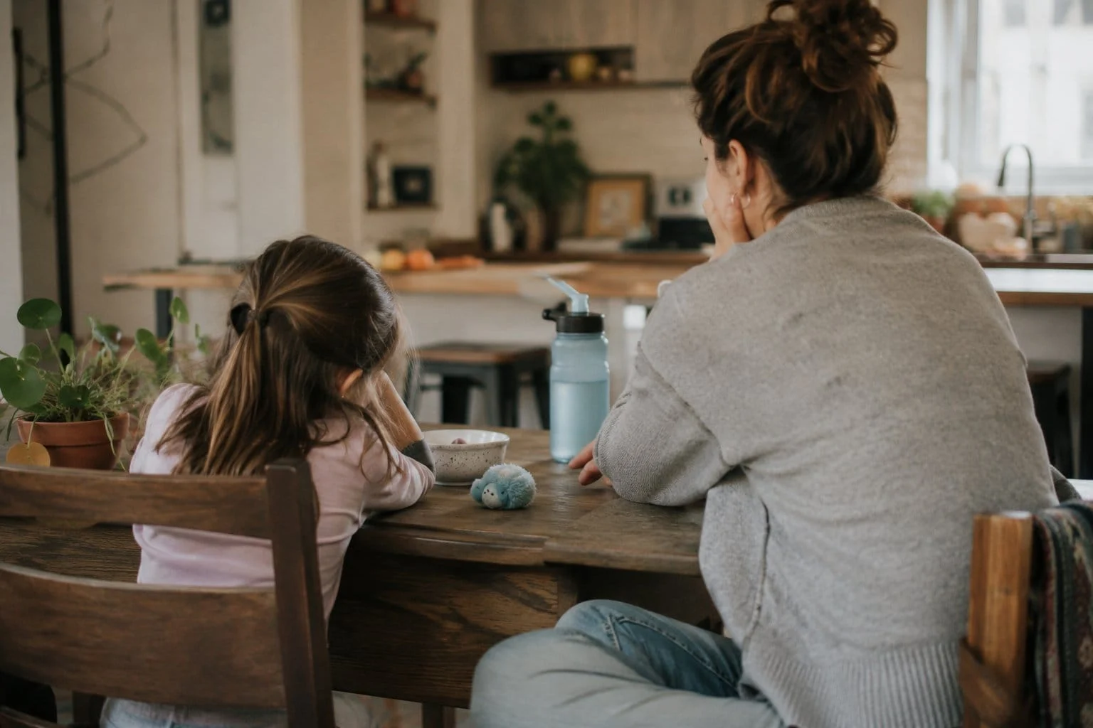 Mother and daughter packing a school bag at the breakfast table with a quiet fidget nearby