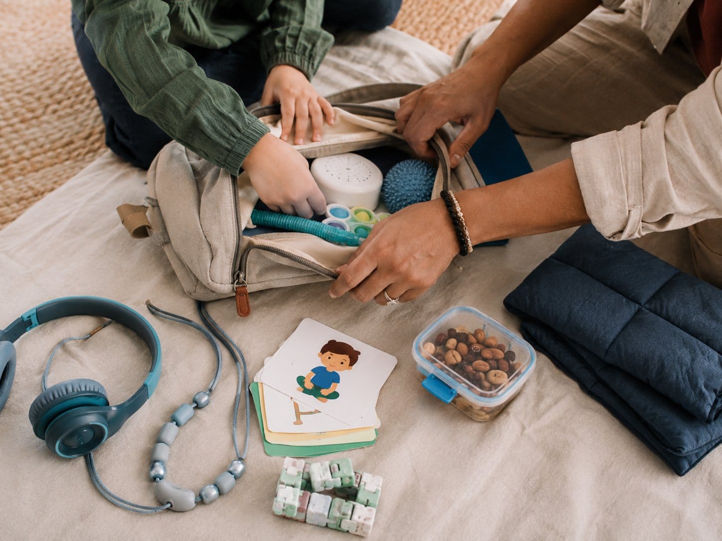 Parent and child packing a small sensory bag with headphones and visual cards