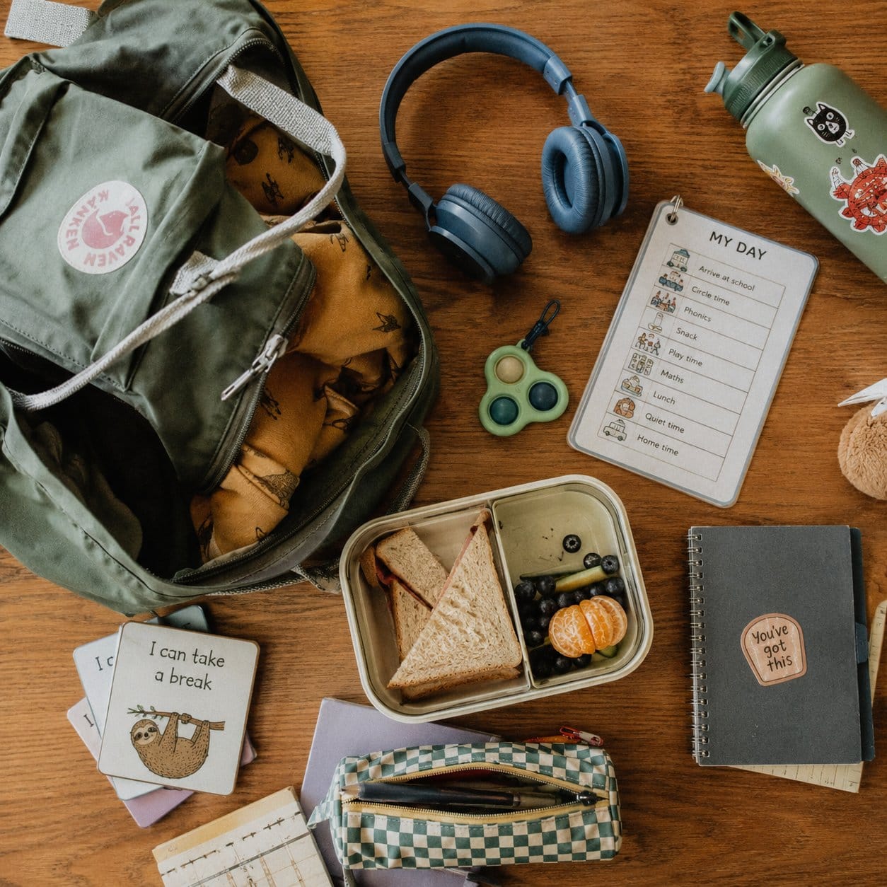 School sensory kit flatlay with headphones, visual schedule, lunchbox and small fidget tool