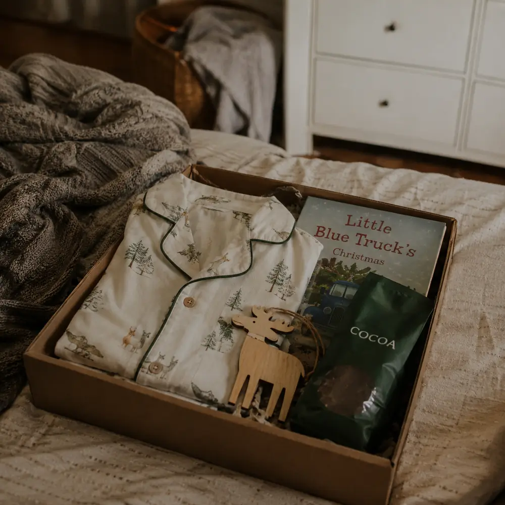 A flat lay of Christmas Eve box contents including socks, a book and a hot chocolate sachet on a wooden surface
