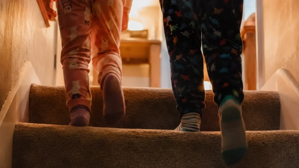 A child in pyjamas waits in sock feet at the top of the stairs on Christmas morning