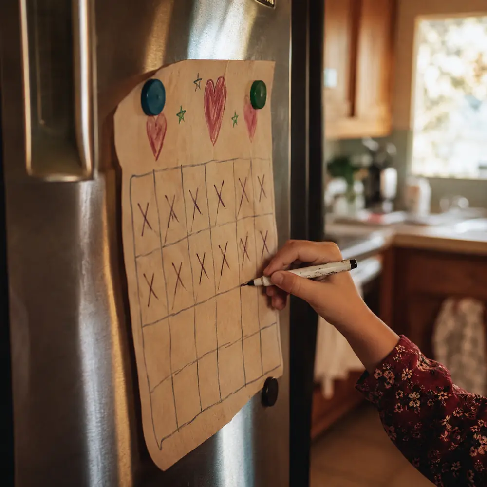 A hand drawn December countdown chart stuck to a fridge door