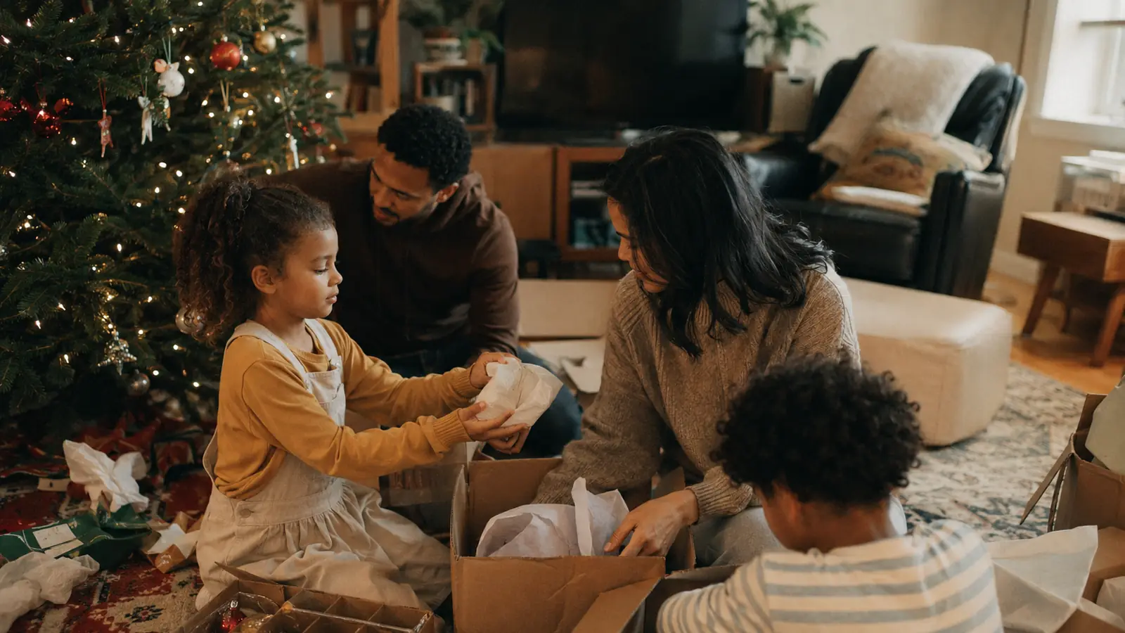 A parent packing Christmas decorations back into a storage box in a living room in early January
