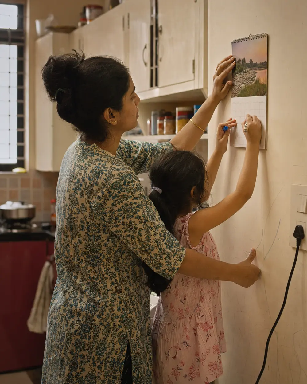 Hands hanging a fresh wall calendar on a kitchen wall in January