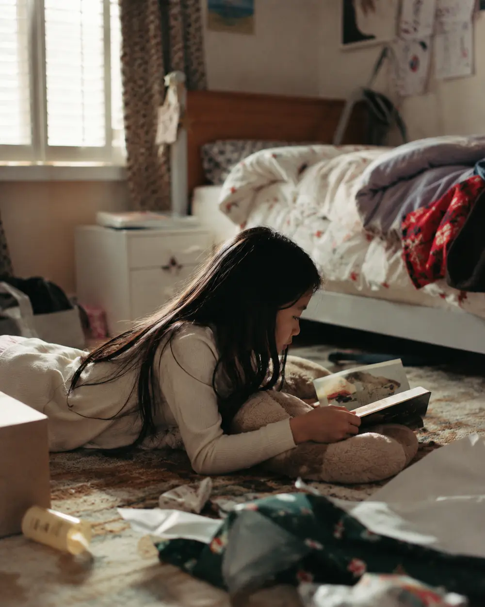 A child sitting alone on a bed in a calm room during a family gathering