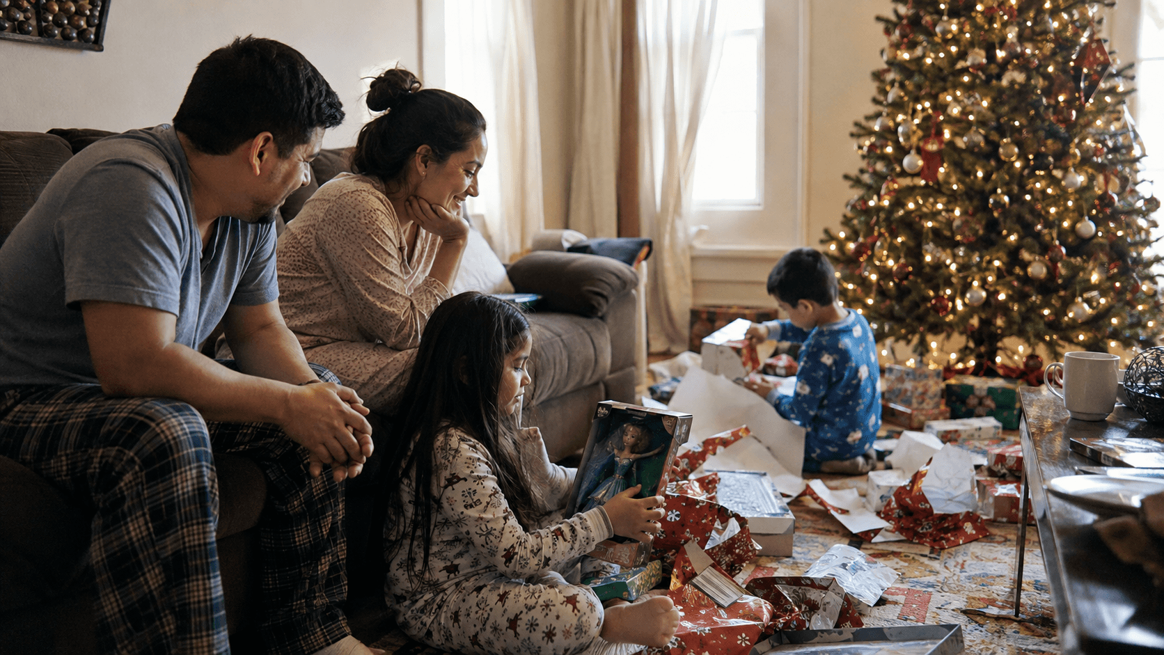 Children sitting on a living room floor on Christmas morning surrounded by opened presents and paper