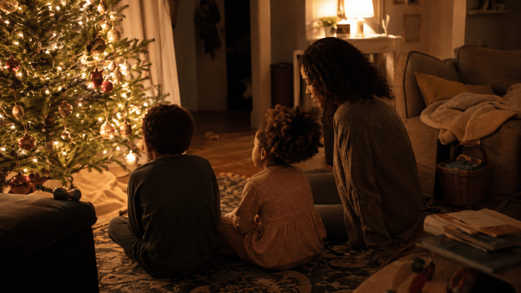 A decorated Christmas tree glowing in a warm living room in the evening with toys on the rug