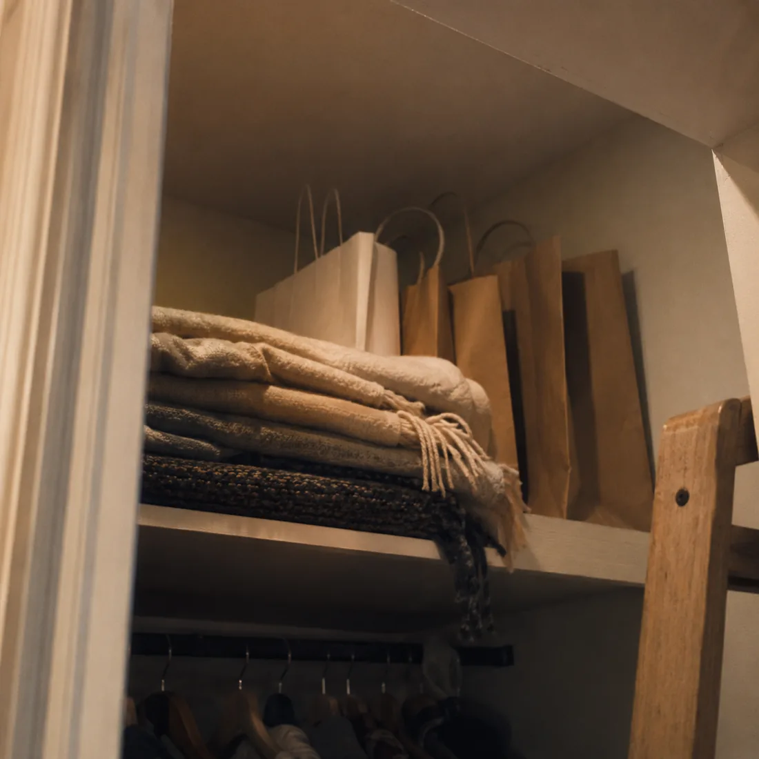 Gift bags stacked on a high closet shelf out of reach
