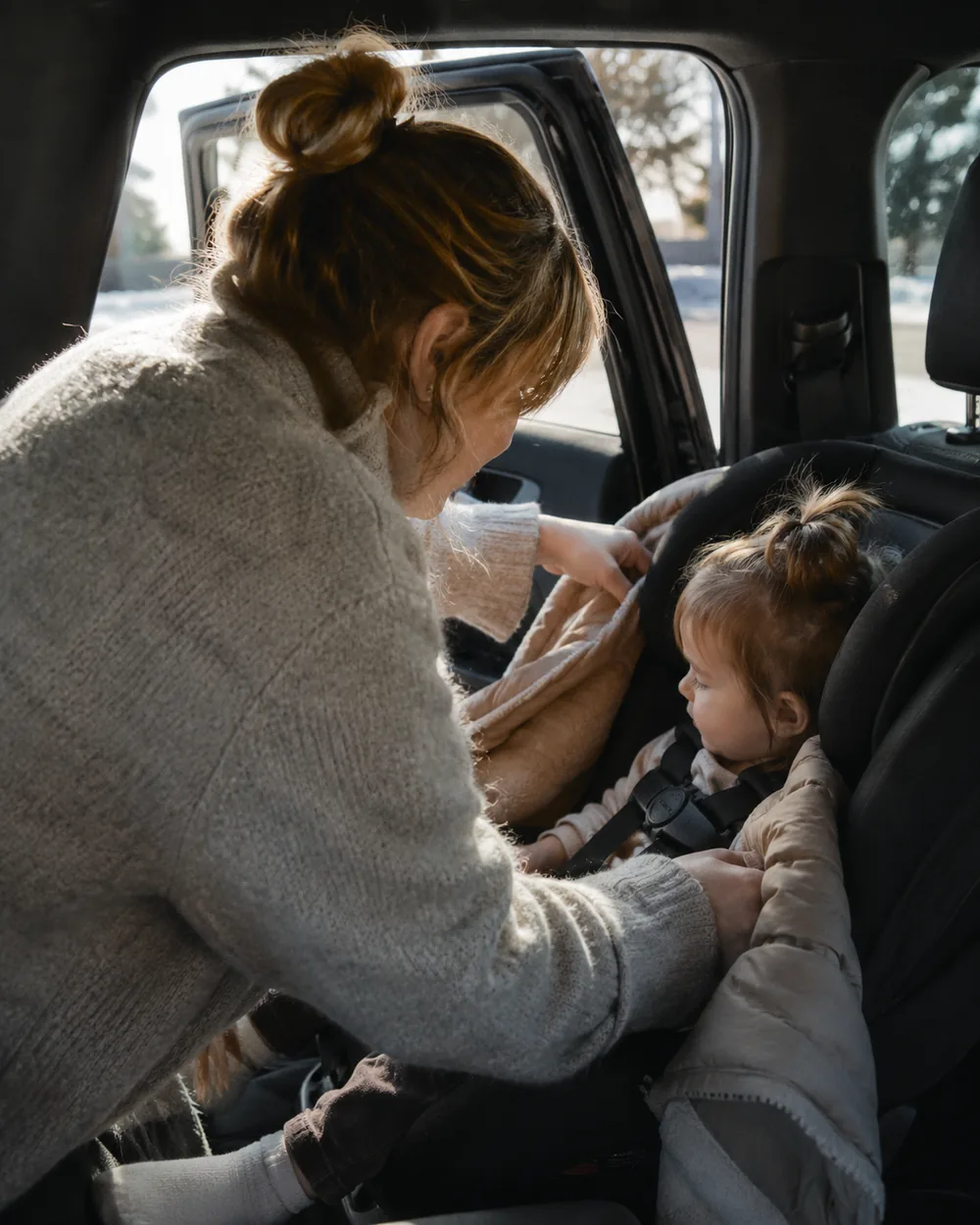 A winter coat laid over a fastened car seat harness instead of worn underneath it