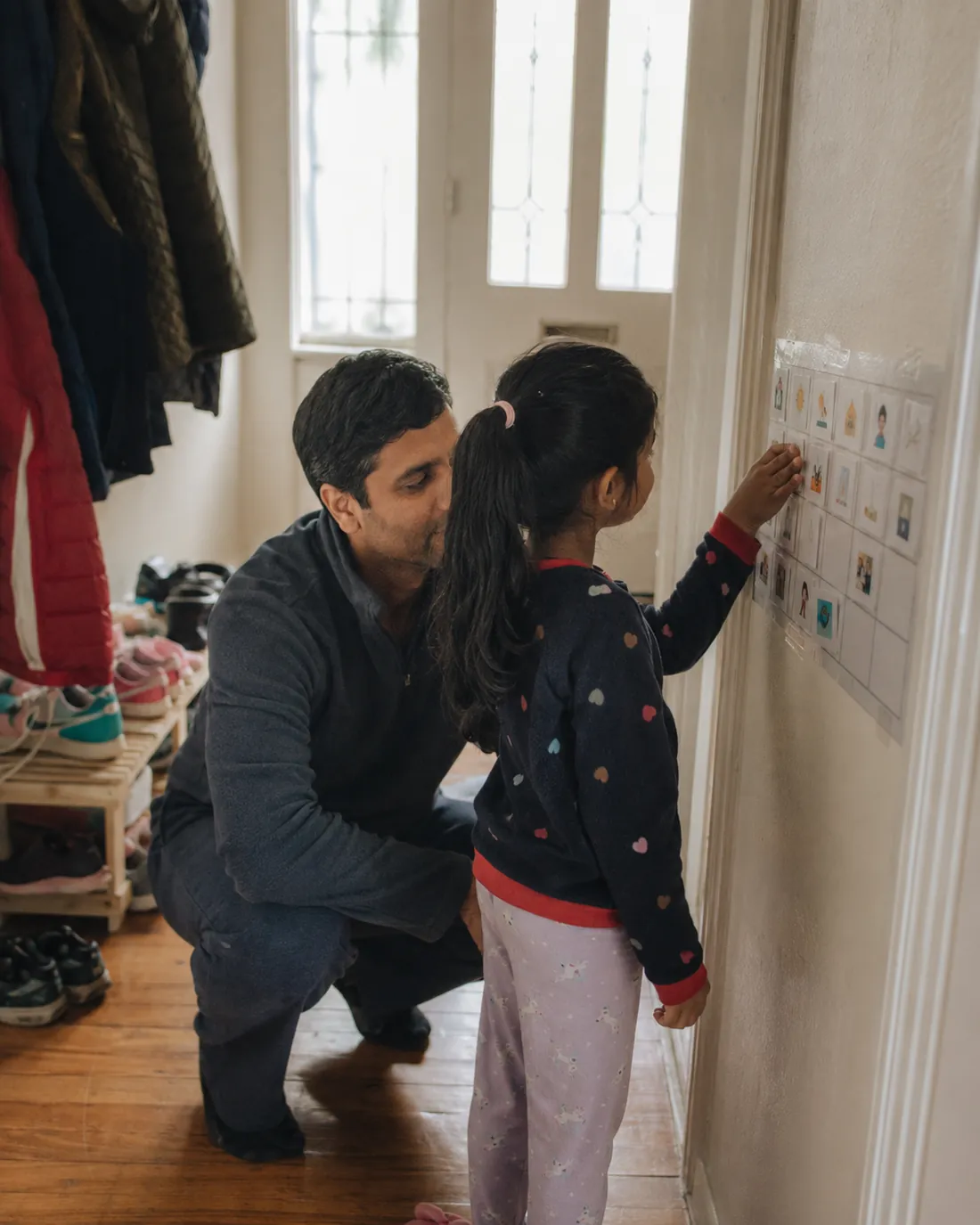 A parent and child point at a visual schedule taped to the wall