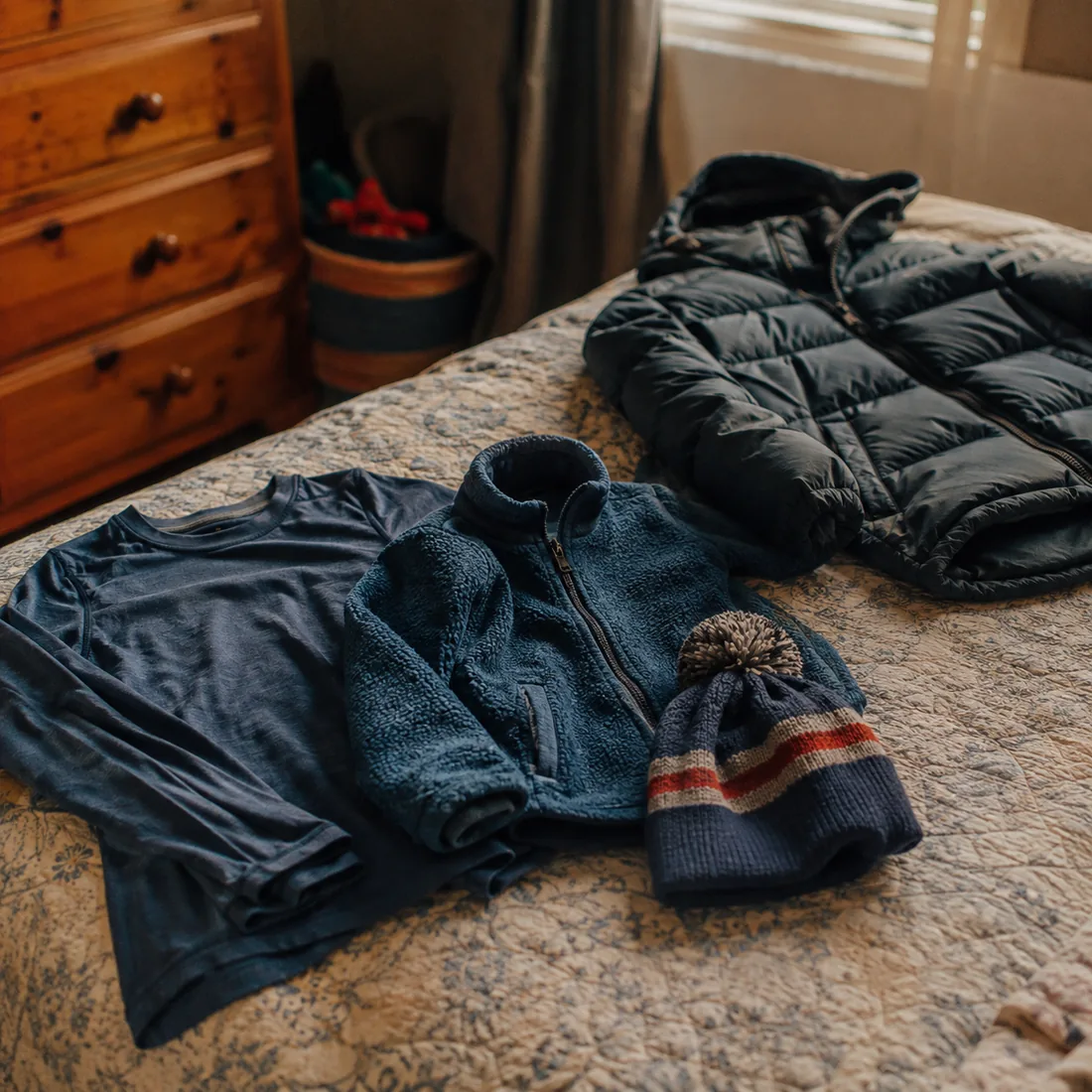 A folded fleece and thin layers laid out instead of a bulky winter coat
