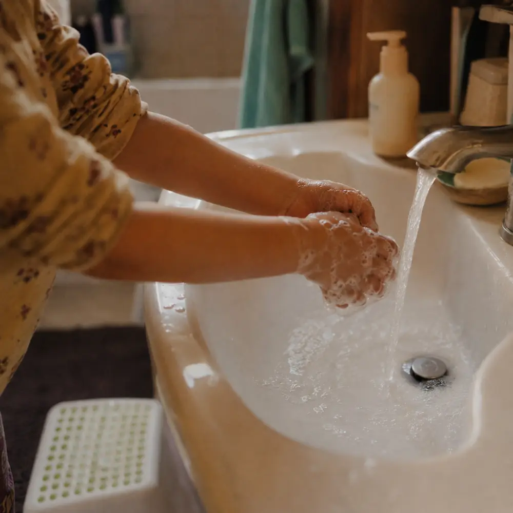 A child washing their hands with soap at a bathroom sink