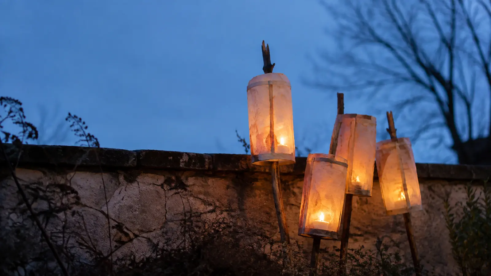 Children carrying handmade paper lanterns along a path at dusk